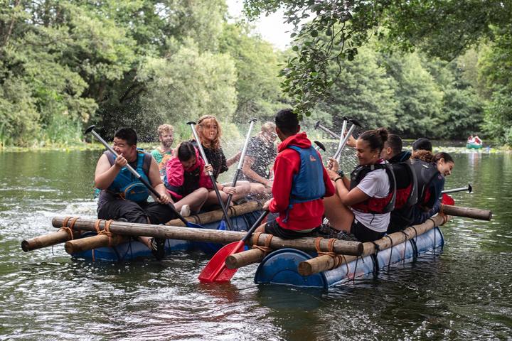 Students paddling a raft they built on the river