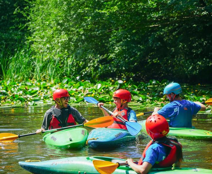 Group of campers in helmets kayaking together