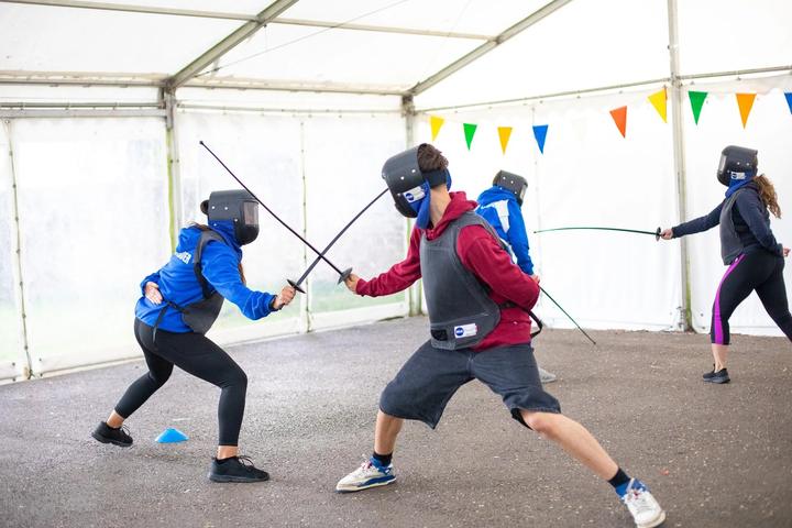 Two campers fencing in the activity tent