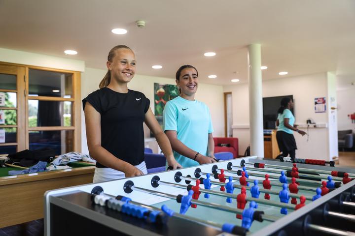 Two campers playing table football in the players' lounge