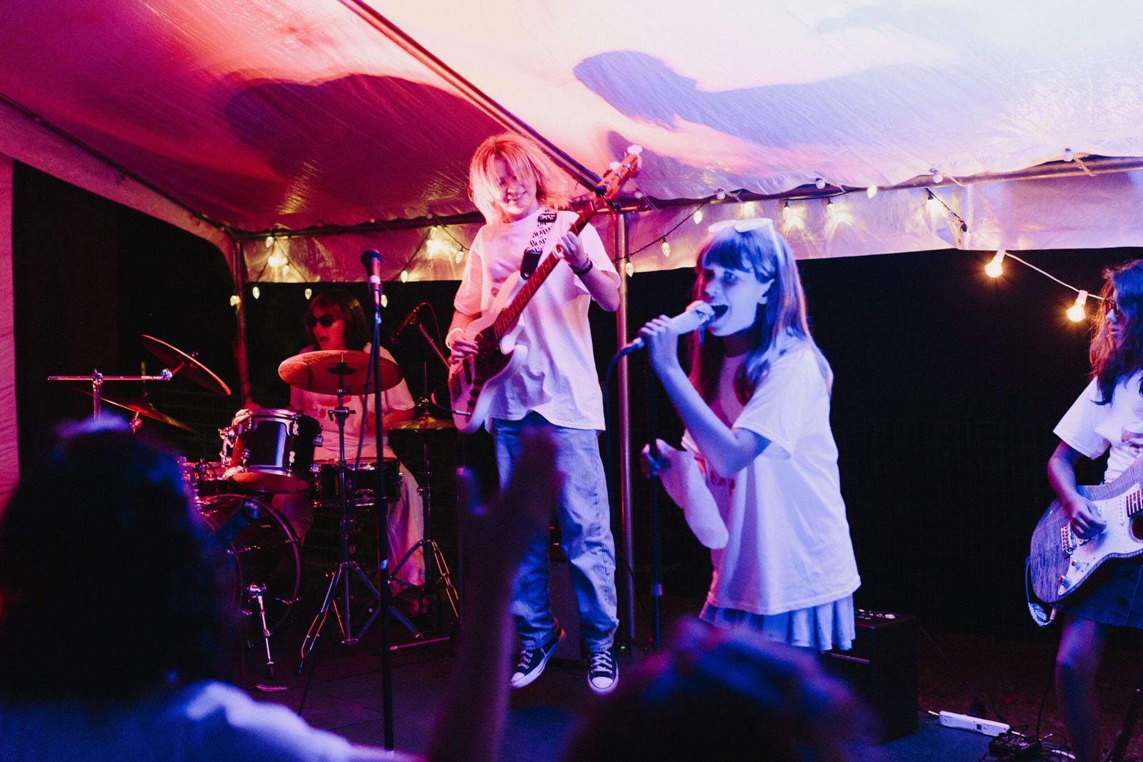 Camper band performing on an outdoor stage under string lights