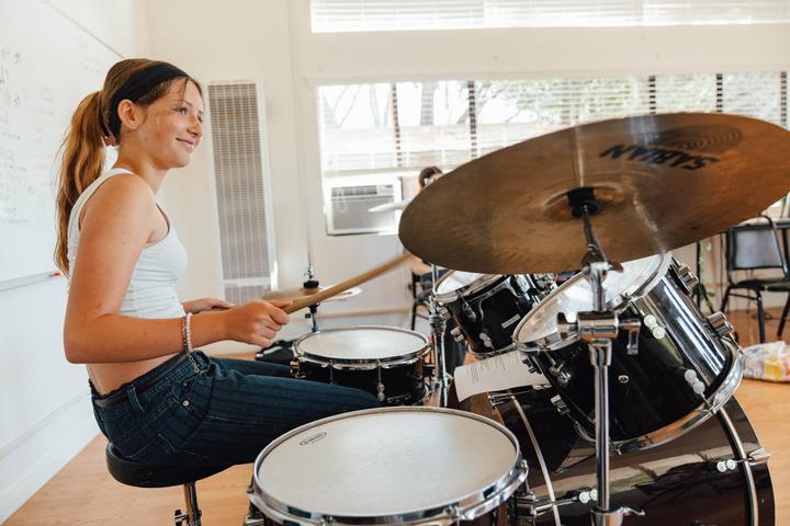 Smiling camper playing a drum kit
