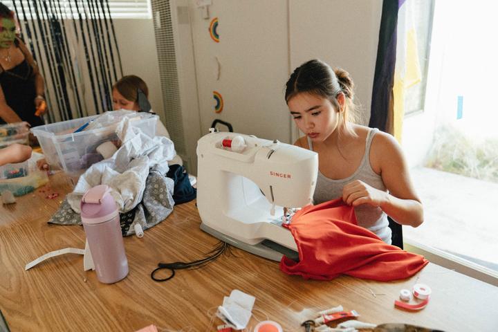 Camper sewing a garment at a sewing machine in the fashion studio