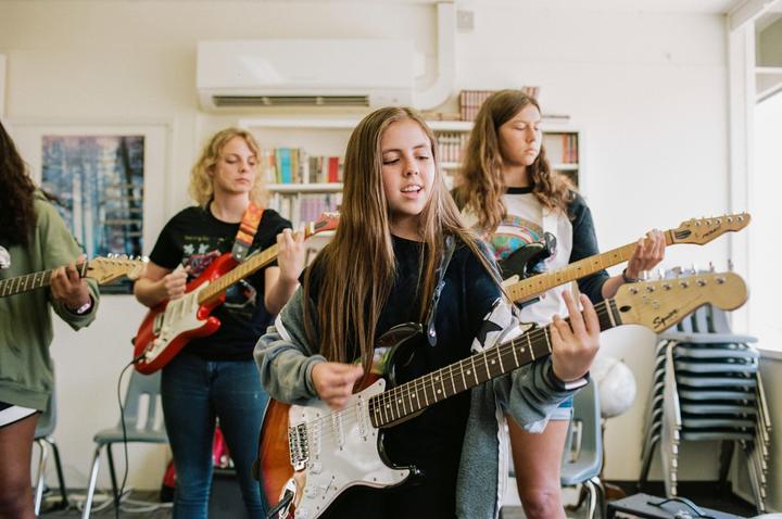 Group of campers rehearsing together on electric guitars