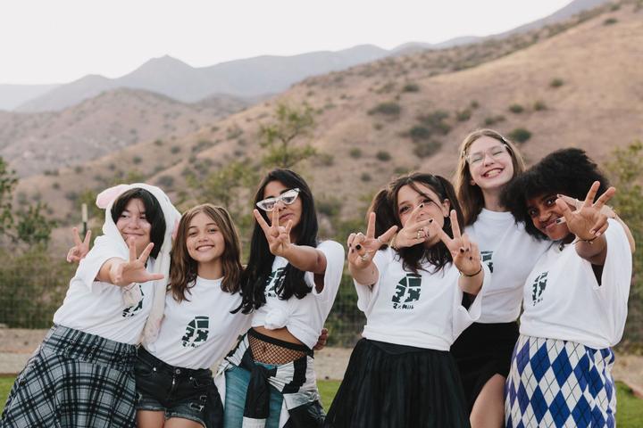 Group of campers posing on a hillside with mountains behind