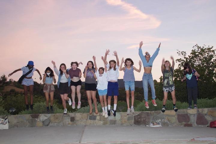 Campers jumping for a photo at sunset
