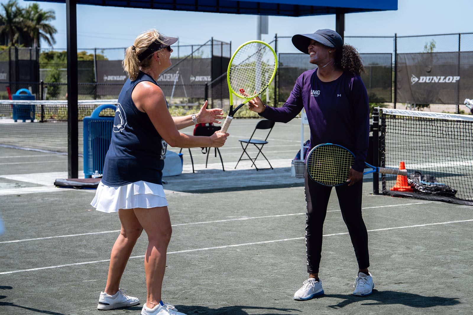 Two adult players laughing together on court between drills
