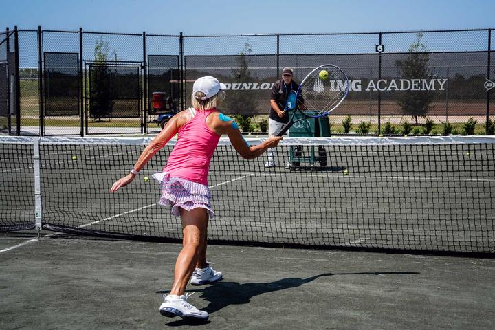An adult camper hitting a forehand in a drill