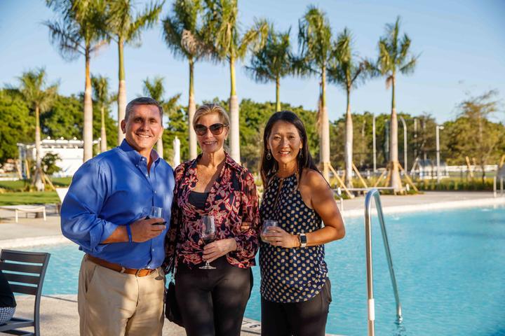 Three adult campers with drinks by the pool after a day of tennis