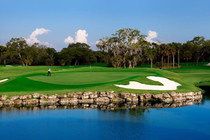A green on the 18-hole golf course, framed by water and trees