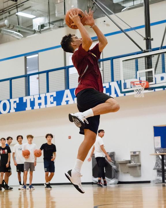A camper going up for a jump shot in the gym