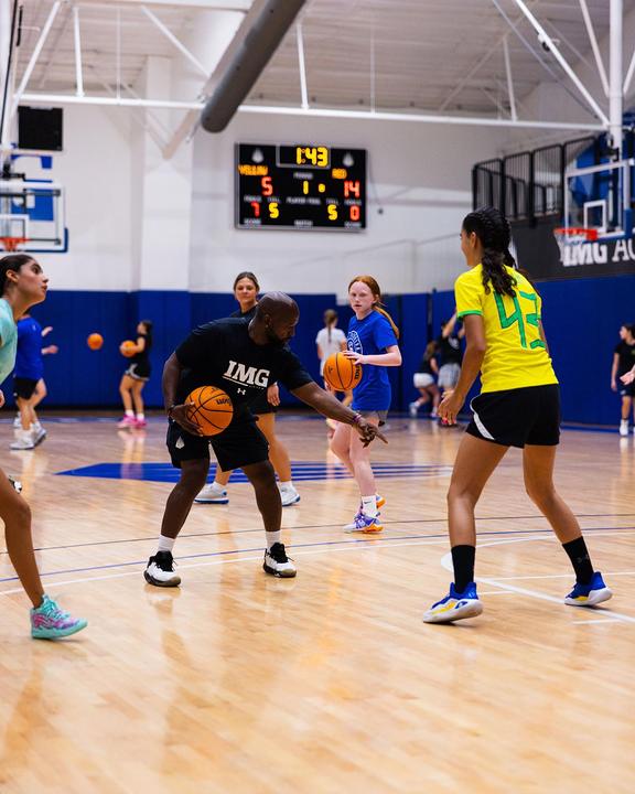A coach running a defensive drill with a group of girls