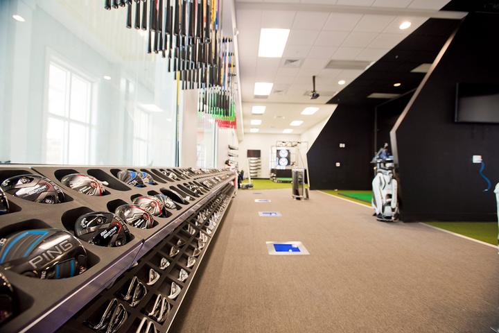 The club-fitting studio with rows of driver heads and a hitting bay