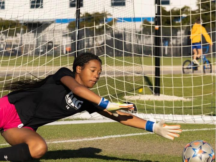 A goalkeeper diving to save a low shot
