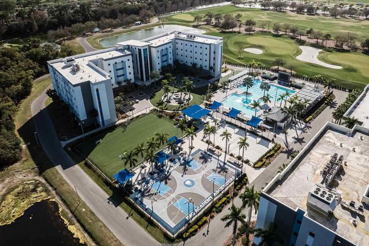 Aerial view of the residence halls, pool and outdoor courts, with the golf course behind