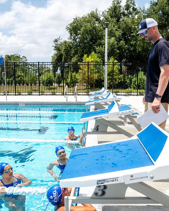 A coach talking to swimmers at the starting blocks