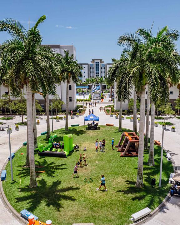 The palm-lined lawn between the residence halls, set up with inflatables for an afternoon event