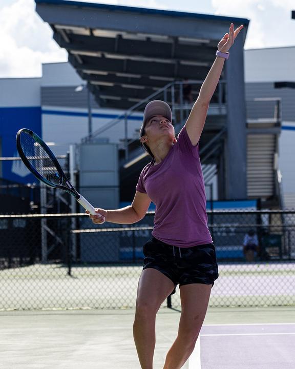 A girl serving on a hard court