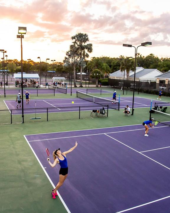 Players on the outdoor hard courts at sunset