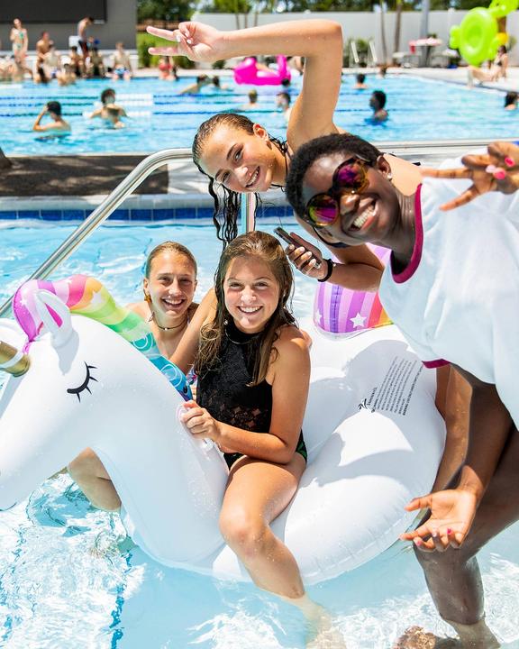Campers posing with an inflatable unicorn at a pool party
