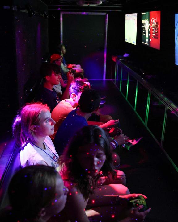 Campers playing video games in the neon-lit gaming truck