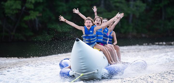 Campers cheering on a towed tube on the lake
