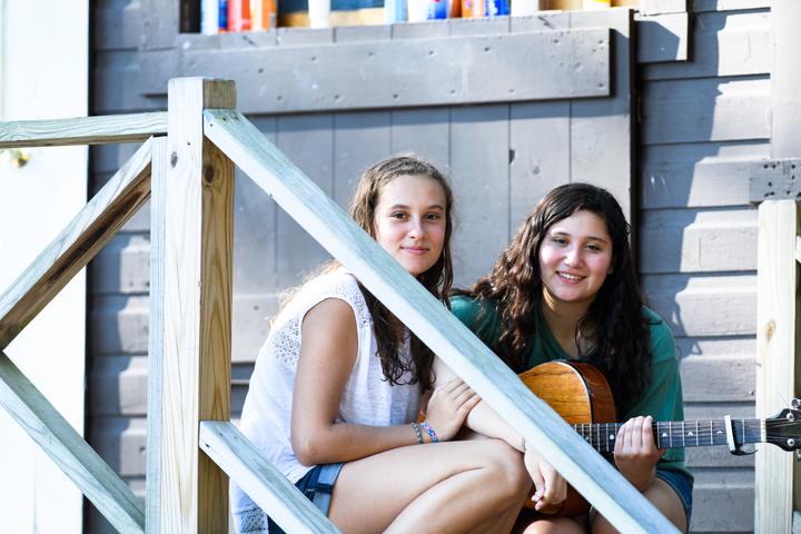 Two campers with a guitar on a cabin porch