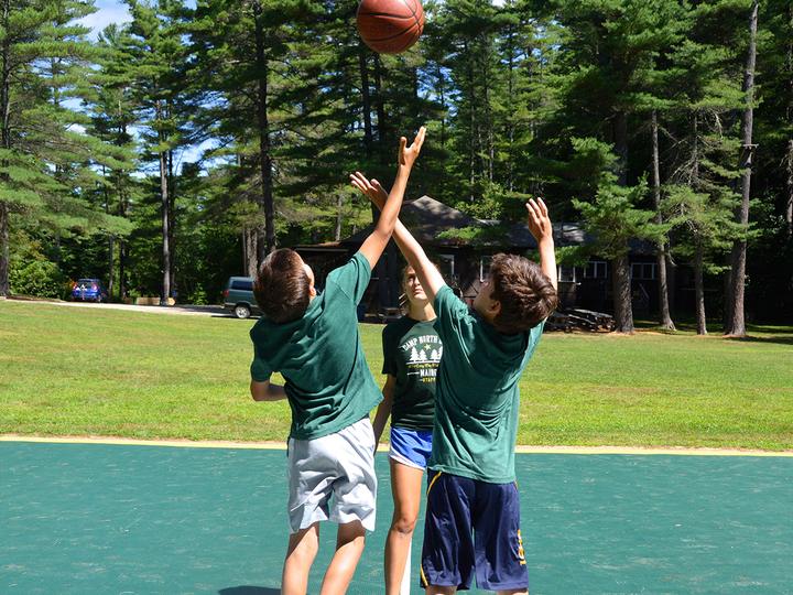 Campers playing basketball under the pines