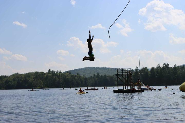 Camper flying off the rope swing over the lake