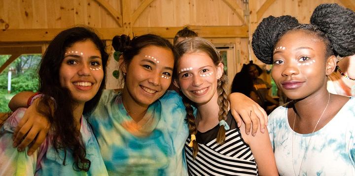 Four friends with face glitter smiling together