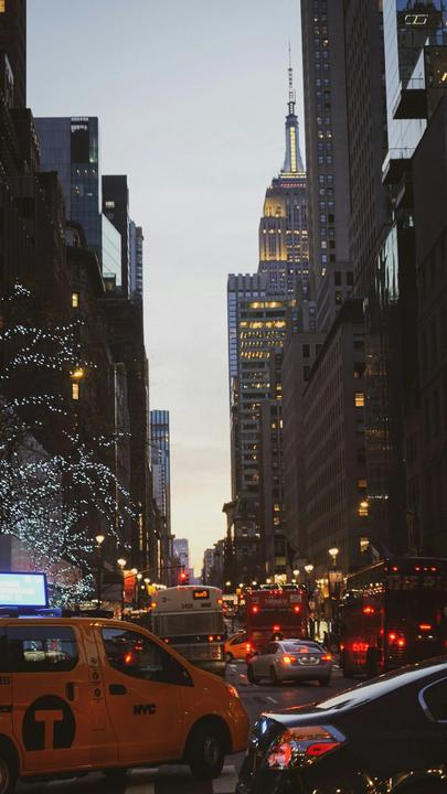 A Manhattan street with holiday lights and a yellow cab