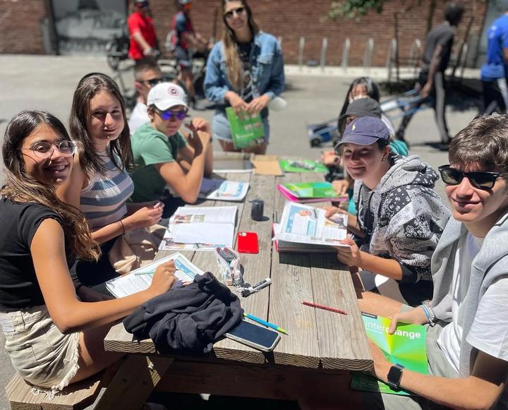 Teens working through a lesson at an outdoor table in the city