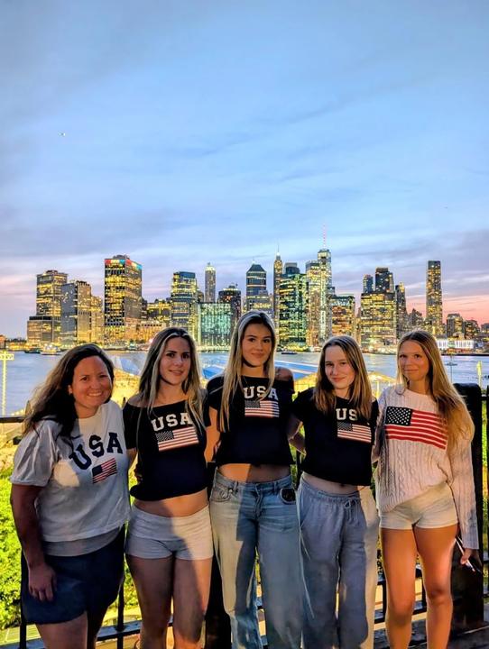 Girls in USA T-shirts in front of the Manhattan skyline at dusk