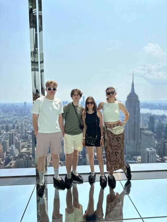 Four young adults at the Summit observatory, Empire State Building behind