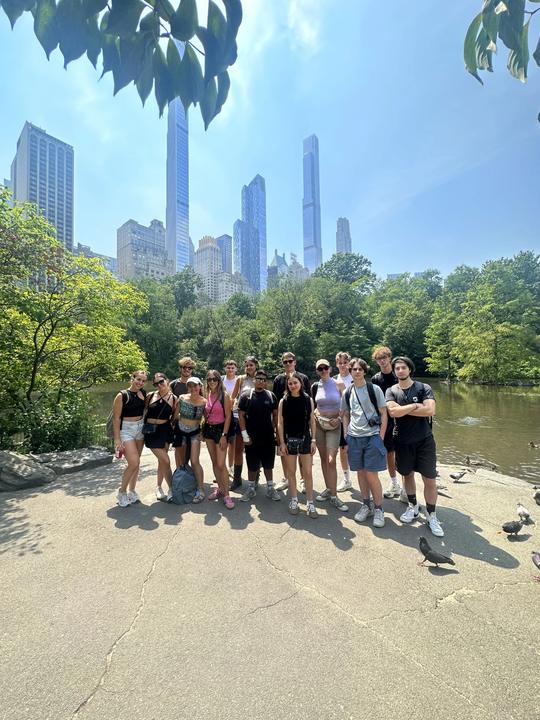 Group by the lake in Central Park, Midtown towers behind