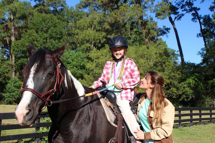 Young camper on a horse with a riding instructor