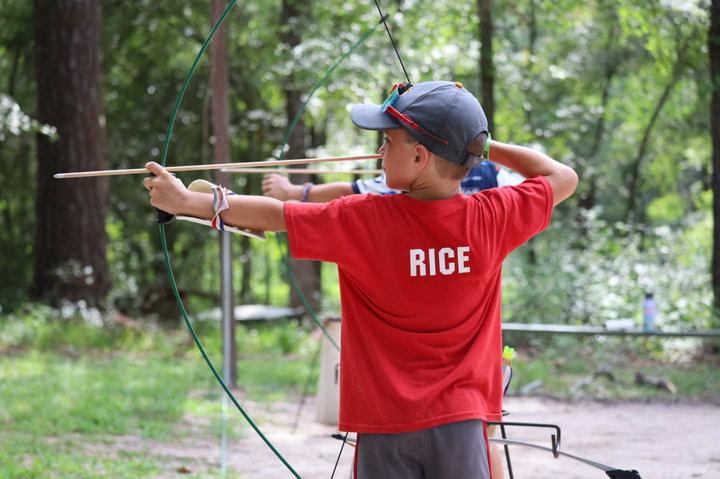 Camper drawing a bow at archery