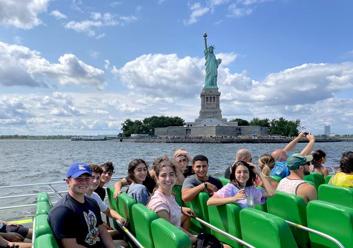 Teens on a boat passing the Statue of Liberty